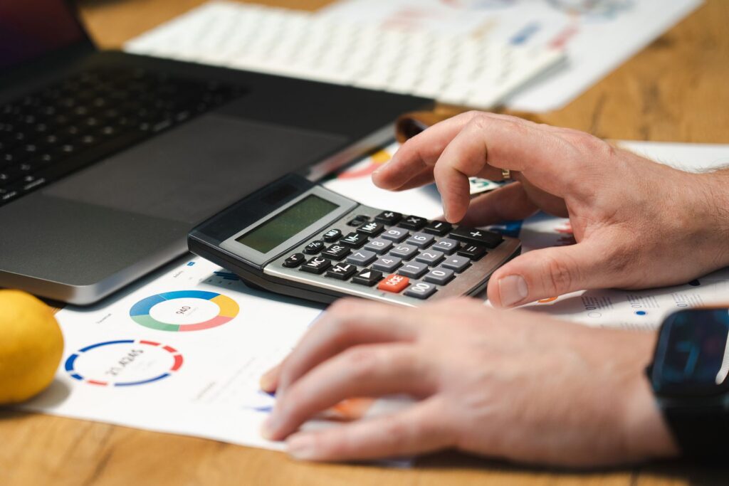 Man analysing finances with a calculator and laptop at his desk