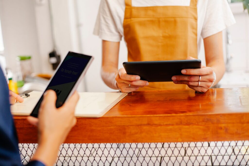 Cafe staff and customer using a smartphone and tablet at the counter