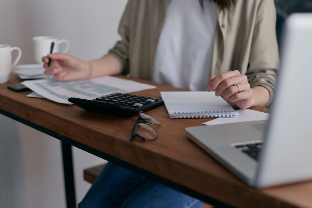 Woman managing finances at home with a laptop and calculator