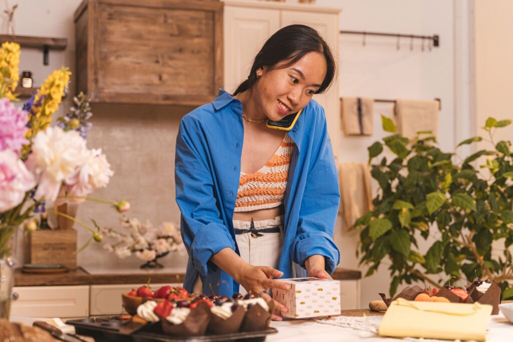 Bakery owner smiling while talking on the phone and packing pastries